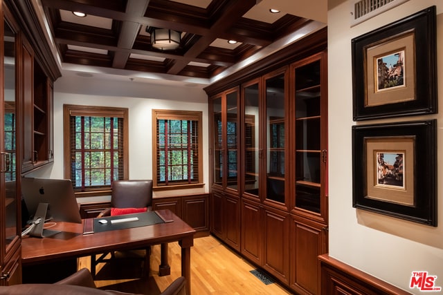 office space featuring light wood-type flooring, coffered ceiling, beam ceiling, and crown molding