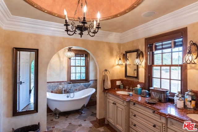 bathroom featuring a tub to relax in, vanity, crown molding, and a raised ceiling