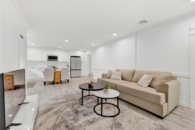 living room featuring light wood-type flooring and crown molding