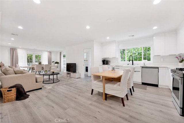 dining area with light hardwood / wood-style floors, sink, ornamental molding, and a healthy amount of sunlight