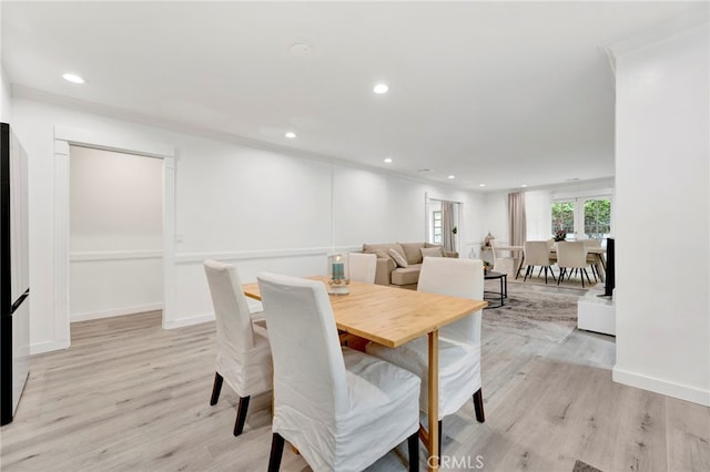 dining room with light hardwood / wood-style floors and crown molding