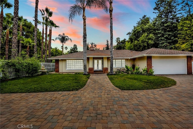 single story home with a garage and a lawn