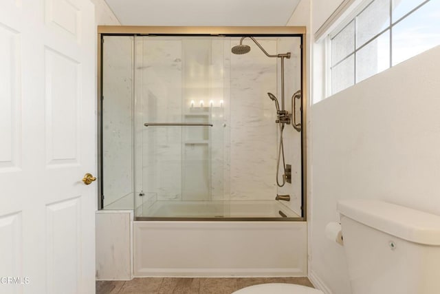 bathroom featuring combined bath / shower with glass door and toilet