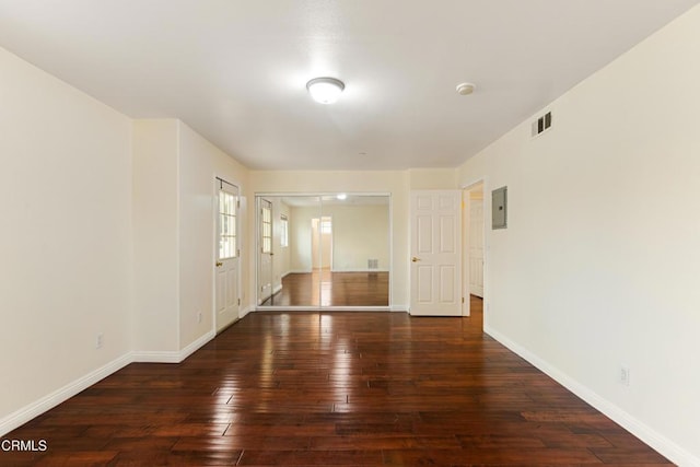 empty room with electric panel and dark hardwood / wood-style flooring