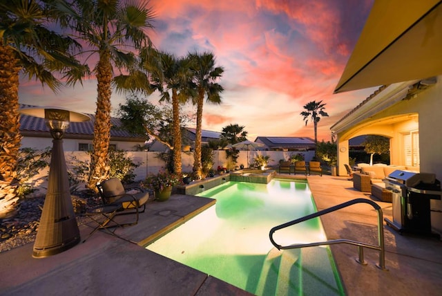 pool at dusk with an in ground hot tub, a patio area, outdoor lounge area, and a grill