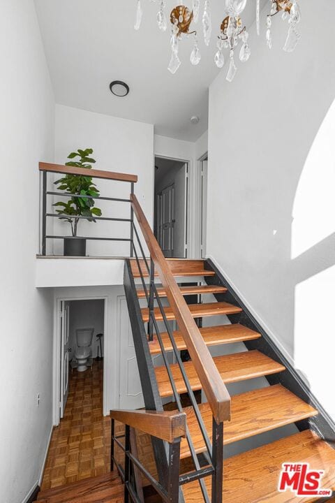 stairs featuring parquet flooring and an inviting chandelier