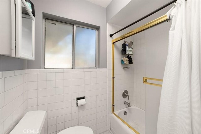 bathroom with tile walls, toilet, shower / tub combo, and a healthy amount of sunlight