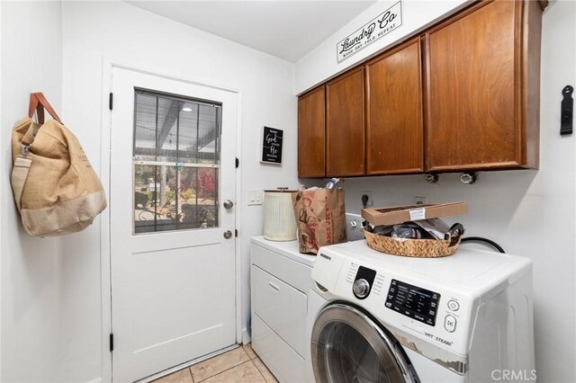 washroom with washer and clothes dryer, light tile patterned floors, and cabinets