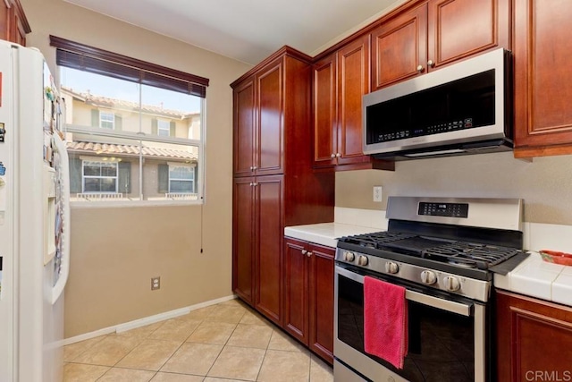 kitchen with stainless steel appliances, tile counters, and light tile patterned floors