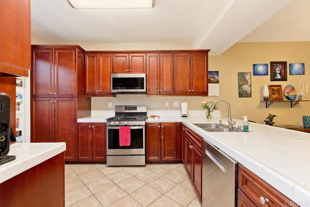 kitchen with tile counters, stainless steel appliances, dark brown cabinets, a sink, and light tile patterned flooring