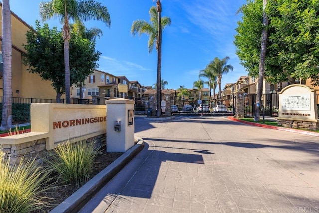 view of street with curbs, a gated entry, a gate, and a residential view