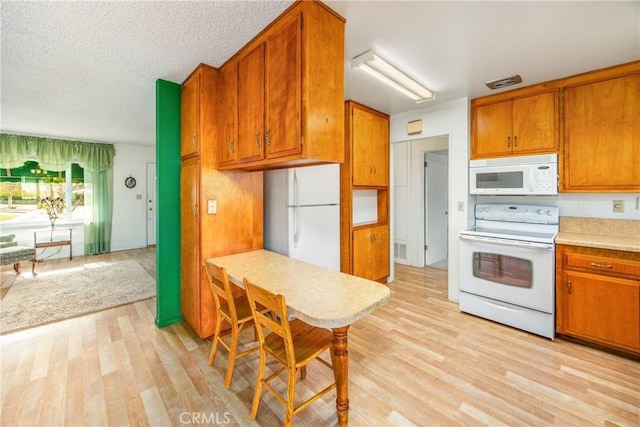 kitchen with white appliances, light hardwood / wood-style flooring, and a textured ceiling