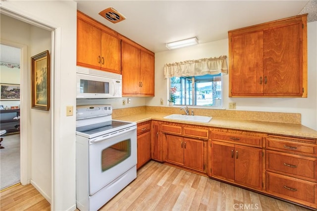 kitchen featuring sink, light wood-type flooring, and white appliances