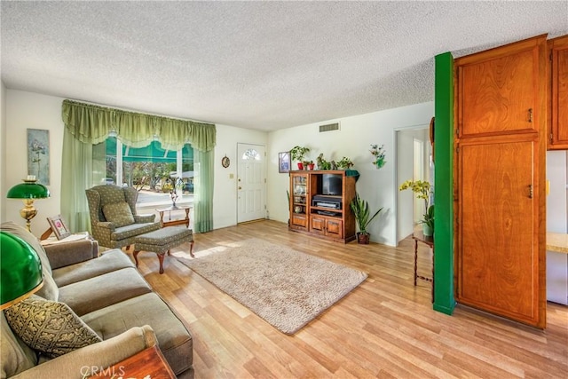 living room featuring light wood-type flooring and a textured ceiling