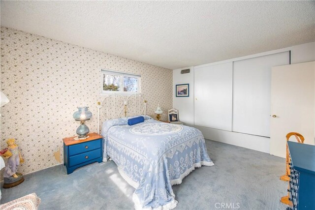 carpeted bedroom with a textured ceiling and a closet