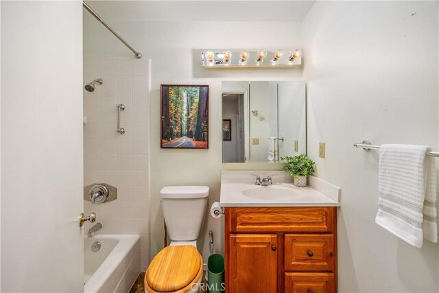 full bathroom featuring tiled shower / bath combo, toilet, and vanity