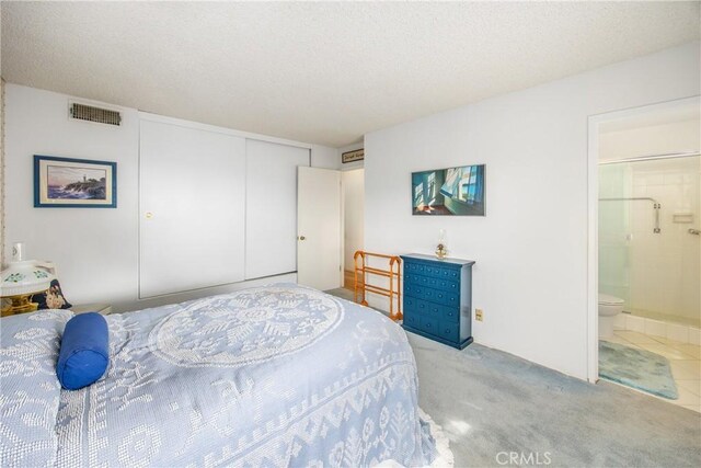 bedroom featuring light colored carpet, connected bathroom, a closet, and a textured ceiling