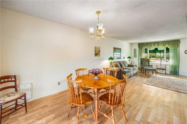 dining area with a textured ceiling, light hardwood / wood-style flooring, and a notable chandelier