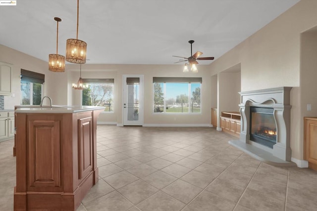 unfurnished living room featuring sink, ceiling fan with notable chandelier, and light tile patterned floors