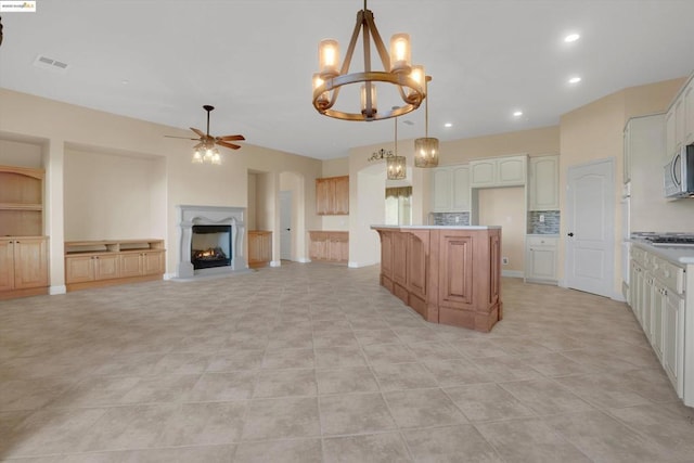 kitchen featuring ceiling fan with notable chandelier, pendant lighting, a center island, and light tile patterned flooring