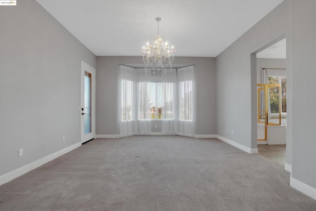 carpeted spare room with a healthy amount of sunlight and a chandelier