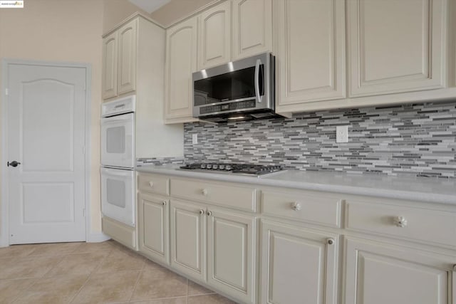 kitchen featuring light tile patterned flooring, decorative backsplash, and stainless steel appliances