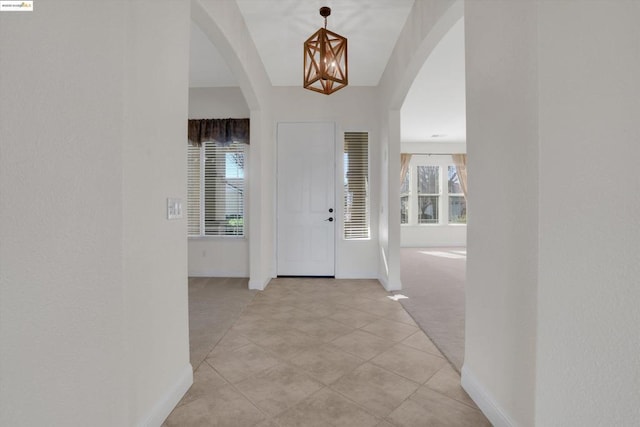 carpeted foyer entrance with a chandelier