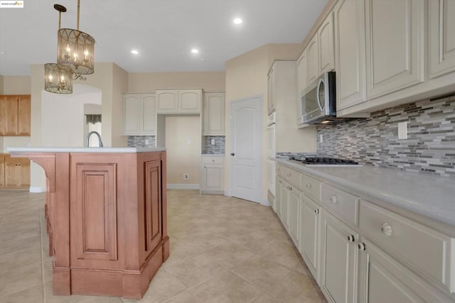 kitchen with tasteful backsplash, sink, decorative light fixtures, an island with sink, and stainless steel appliances