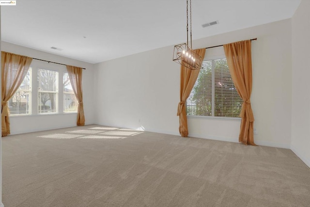 carpeted empty room featuring an inviting chandelier