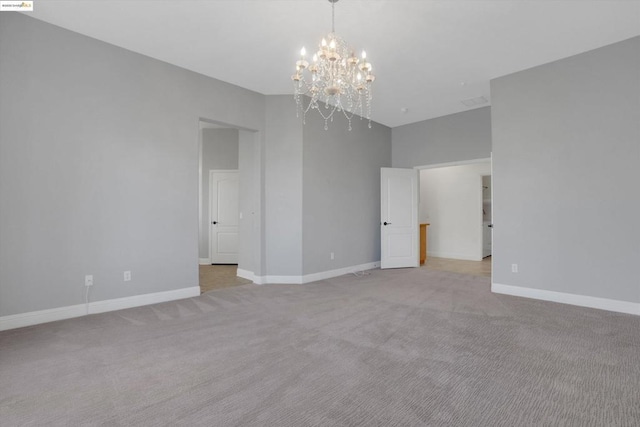 unfurnished room with light colored carpet and a notable chandelier