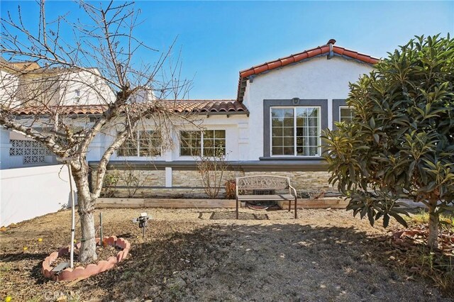 back of property featuring stucco siding and a tiled roof