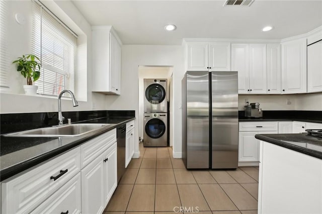 kitchen with stacked washer / drying machine, sink, white cabinetry, stainless steel fridge, and dishwasher