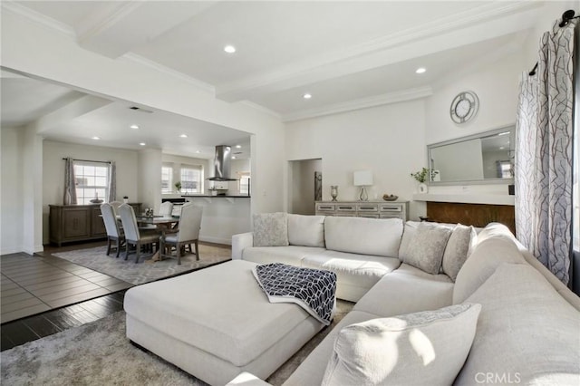 living room featuring baseboards, beam ceiling, wood finished floors, and ornamental molding