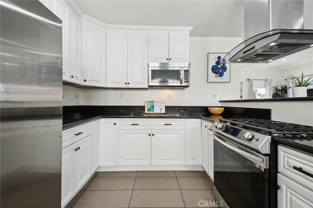 kitchen featuring appliances with stainless steel finishes, island range hood, white cabinets, and tile patterned floors