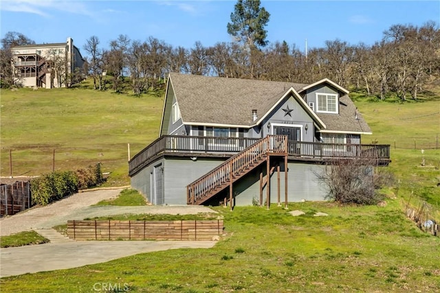 view of front facade featuring a deck, a front lawn, stairway, and a shingled roof