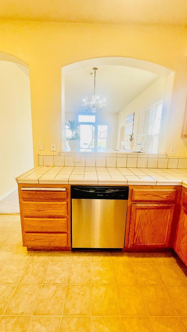 kitchen with pendant lighting, tile countertops, stainless steel dishwasher, and a healthy amount of sunlight