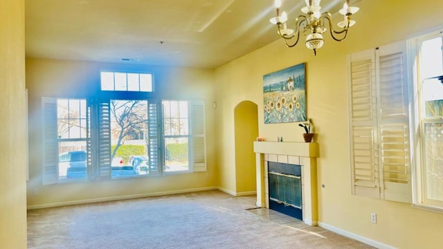 unfurnished living room featuring an inviting chandelier, light colored carpet, and a fireplace