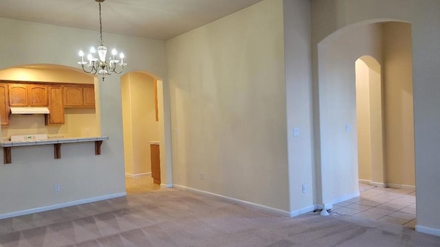 kitchen with pendant lighting, an inviting chandelier, light carpet, and a breakfast bar area