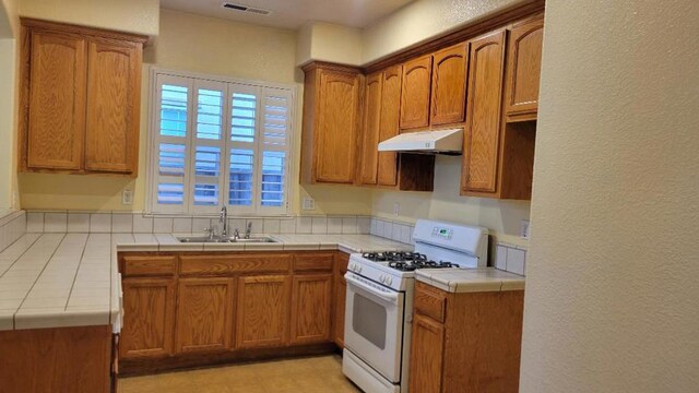 kitchen with tile countertops, sink, and white gas stove