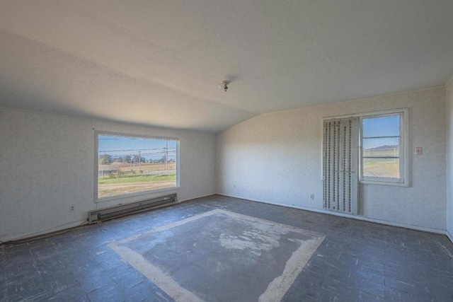 empty room featuring baseboard heating, vaulted ceiling, and a wealth of natural light