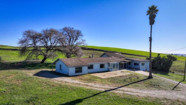 rear view of house with a patio, a lawn, and a rural view