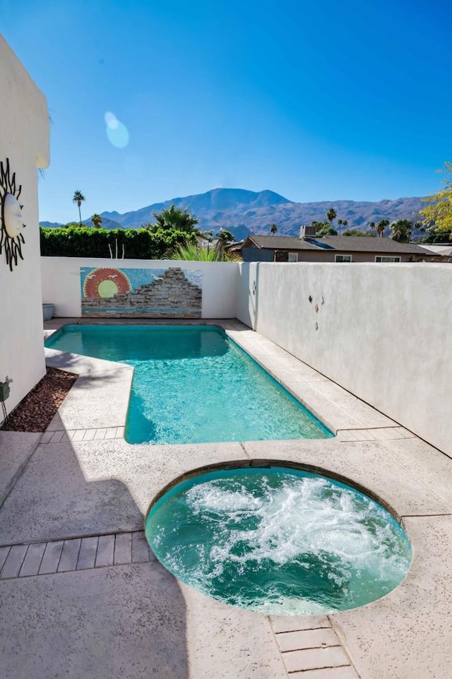 view of swimming pool with an in ground hot tub and a mountain view