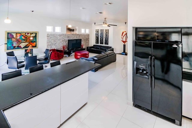 kitchen featuring white cabinetry, black fridge, light tile patterned floors, and decorative light fixtures