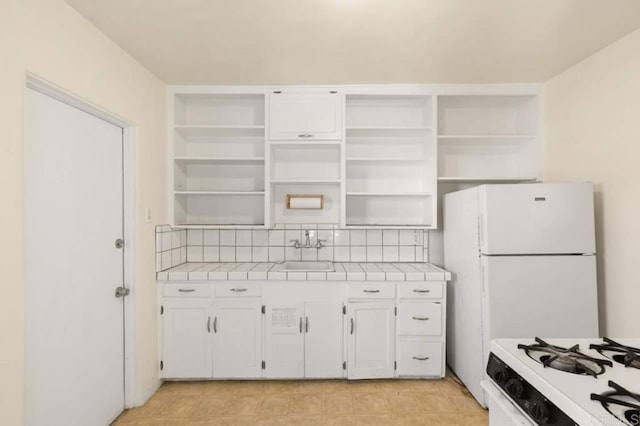 kitchen with sink, white cabinets, tile counters, and tasteful backsplash