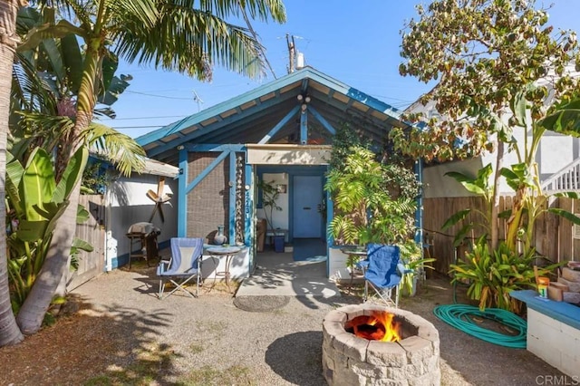 rear view of property with a fire pit, a patio, and an outdoor structure