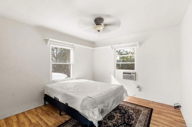 bedroom featuring wood-type flooring, cooling unit, and ceiling fan