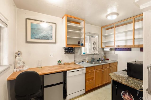 kitchen featuring dishwasher, decorative backsplash, sink, light stone counters, and stainless steel fridge