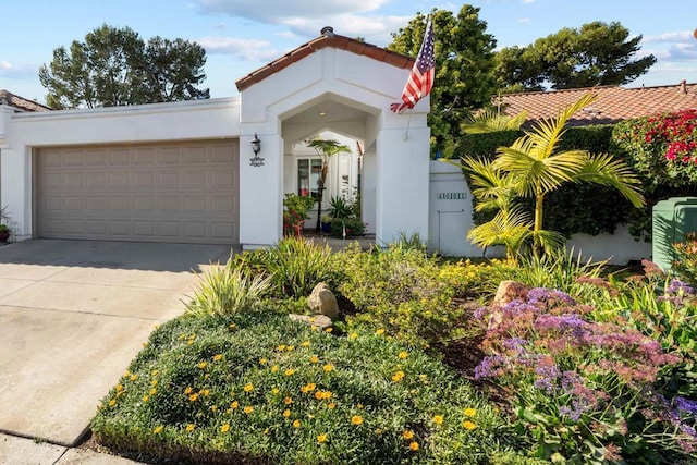 mediterranean / spanish house featuring driveway, an attached garage, and stucco siding