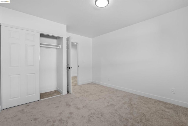 unfurnished bedroom with light carpet and a closet