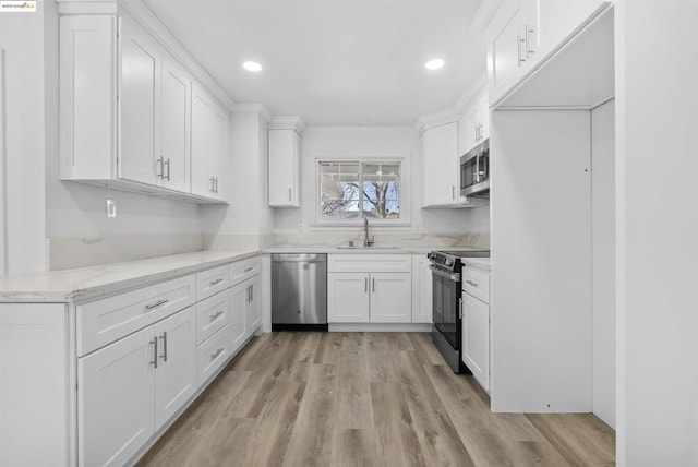 kitchen featuring sink, stainless steel appliances, light stone counters, light hardwood / wood-style floors, and white cabinets